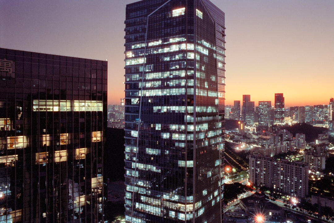 Modern skyscrapers illuminated at dusk with city lights.
